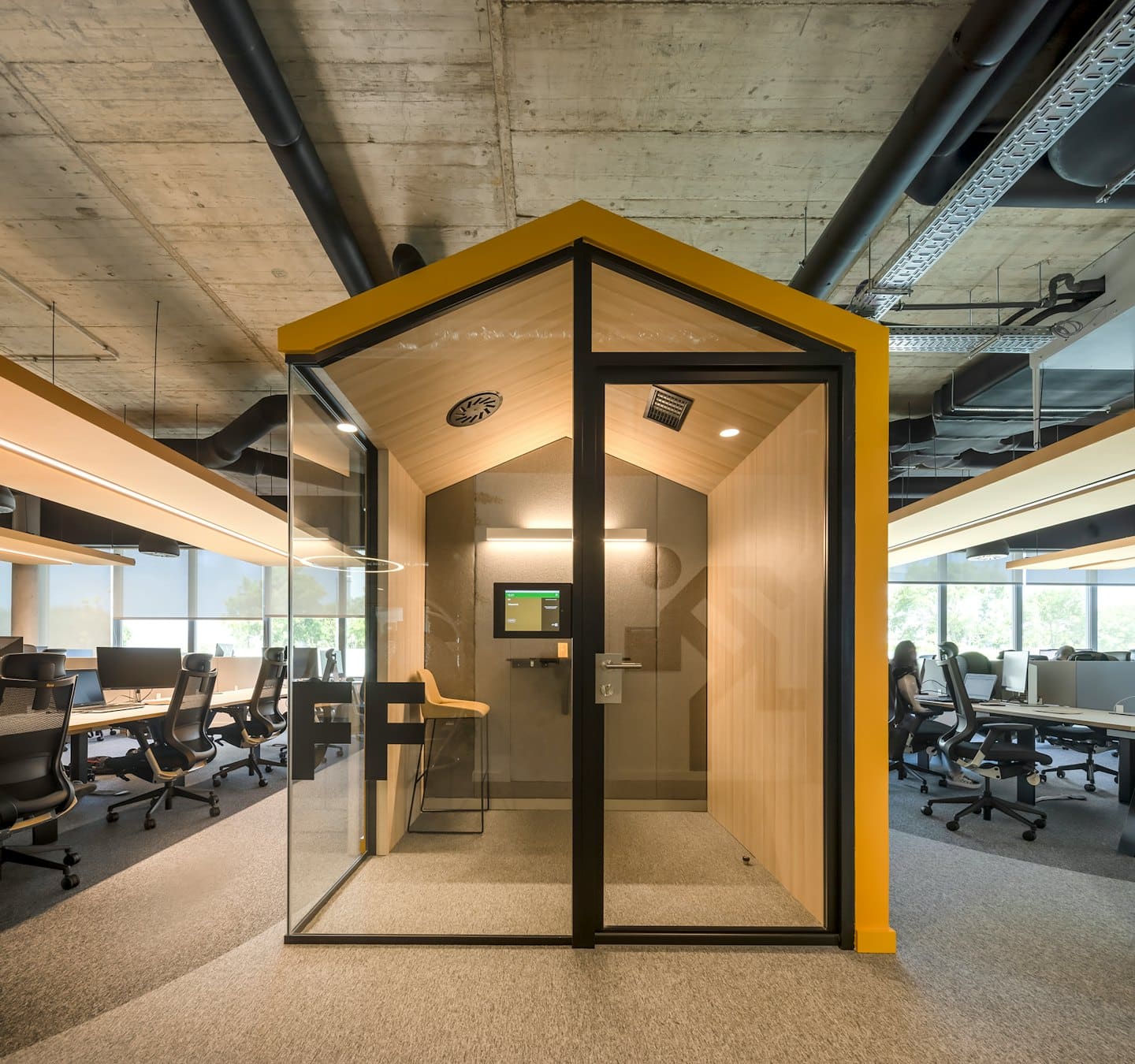 Sarı tavanlı toplantı kabini bulunan modern açık ofis.