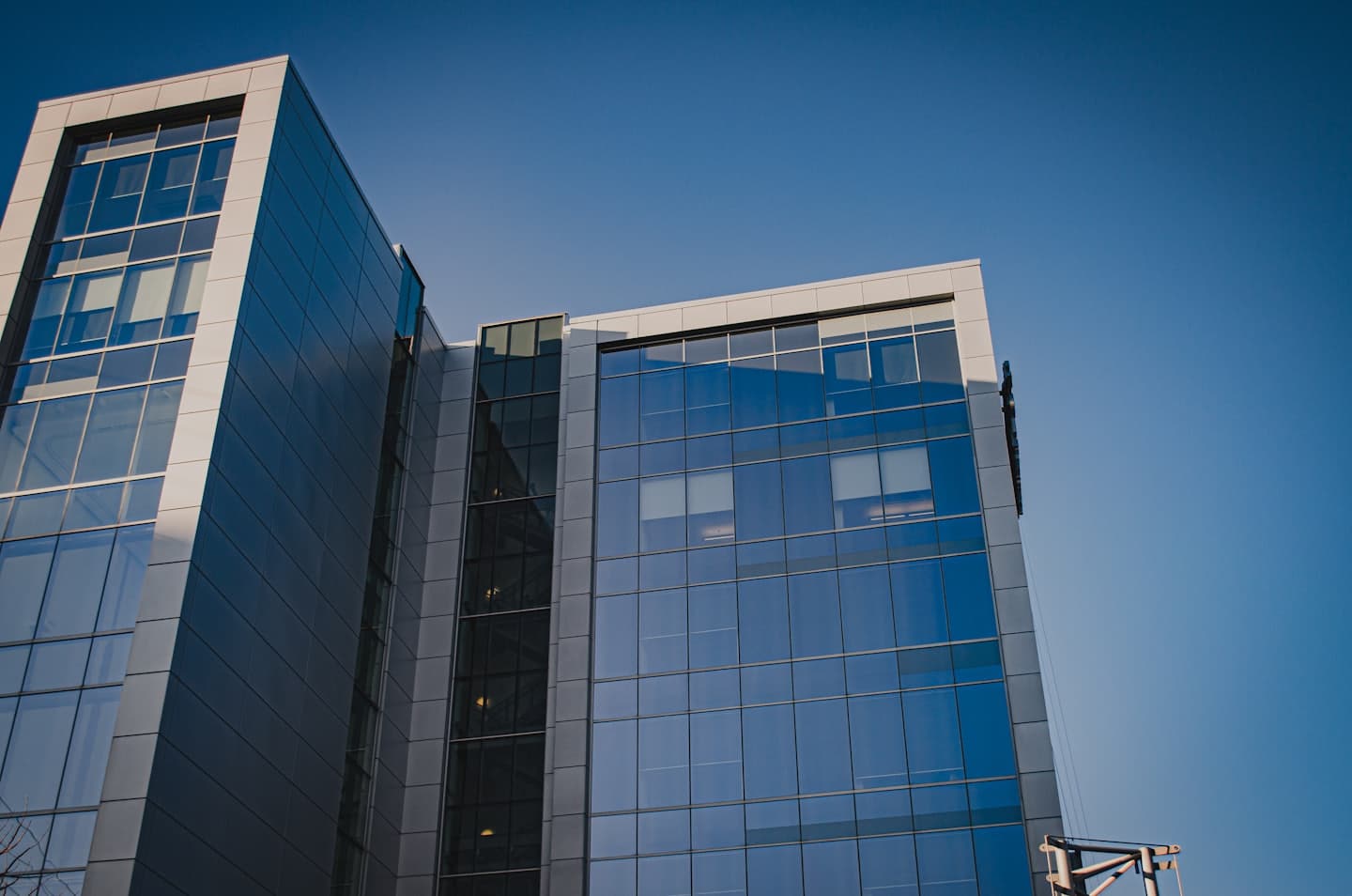 Mavi camlı ve gri panelli modern ofis binası.